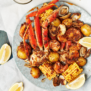 Large seafood boil on galvanized metal plate with crab, potatoes, shrimp, corn, clams