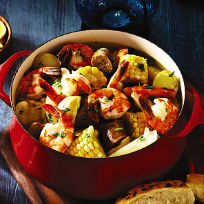 Shrimp boil with sausage, potatoes & corn in a red pot.