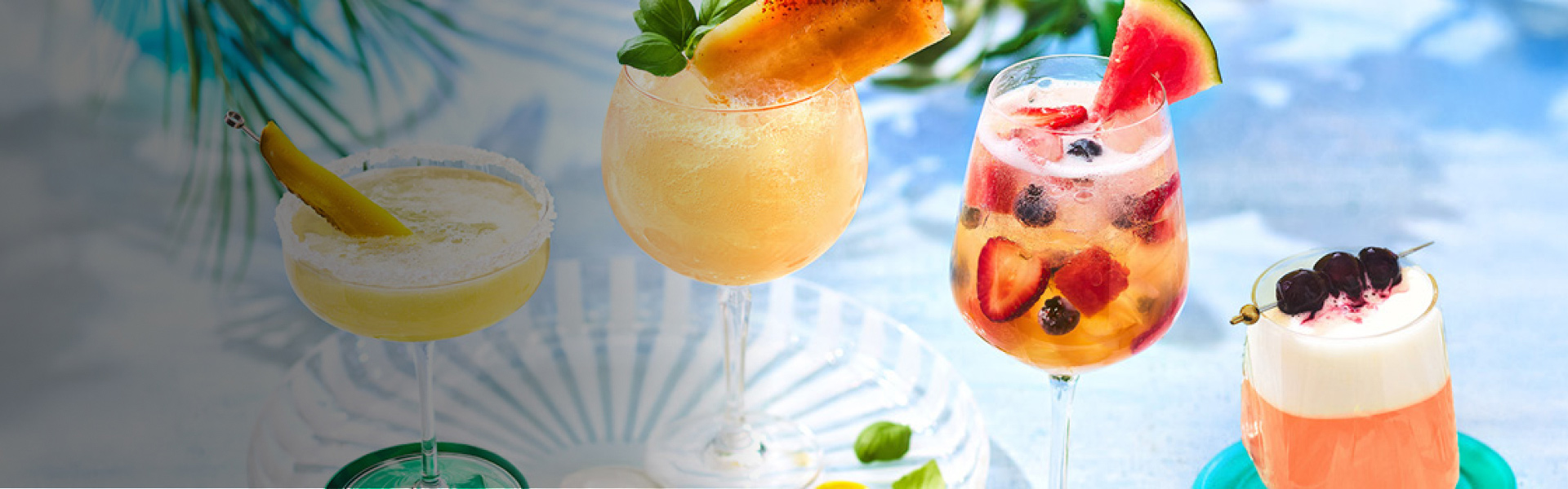Four cocktails on marble background with green in background.