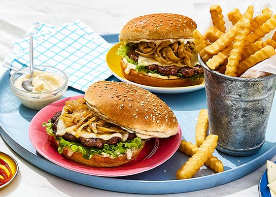 Three French onion smashed burgers with ketchup, mayo and crinkle fries on the side.