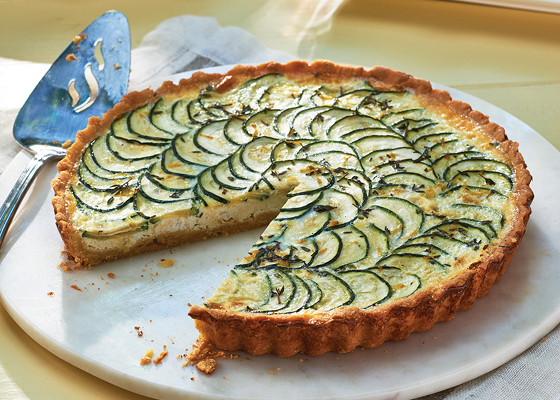 A zucchini tart on a white plate with a slice missing.