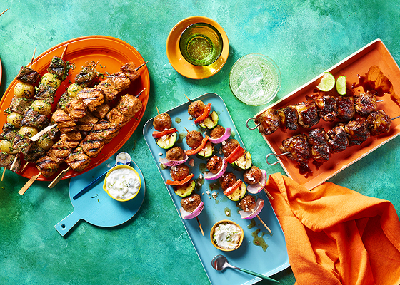 Overhead shot of grilled skewers and kabobs on platters