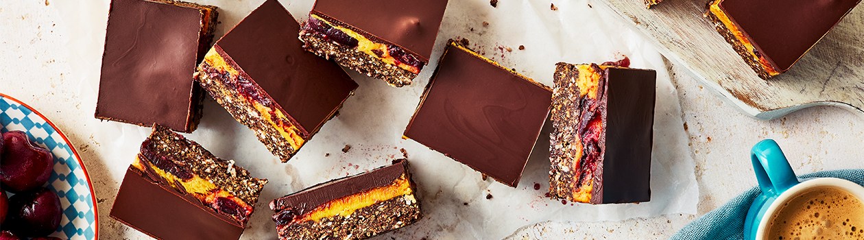 Eight nanaimo bars with fresh cherries in middle