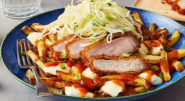 A bowl with the Japanese Tonkatsu Poutine, a cutting board with slices of the pork cutlet, a bowl of green onion, and another bowl of the tonkatsu-style gravy.