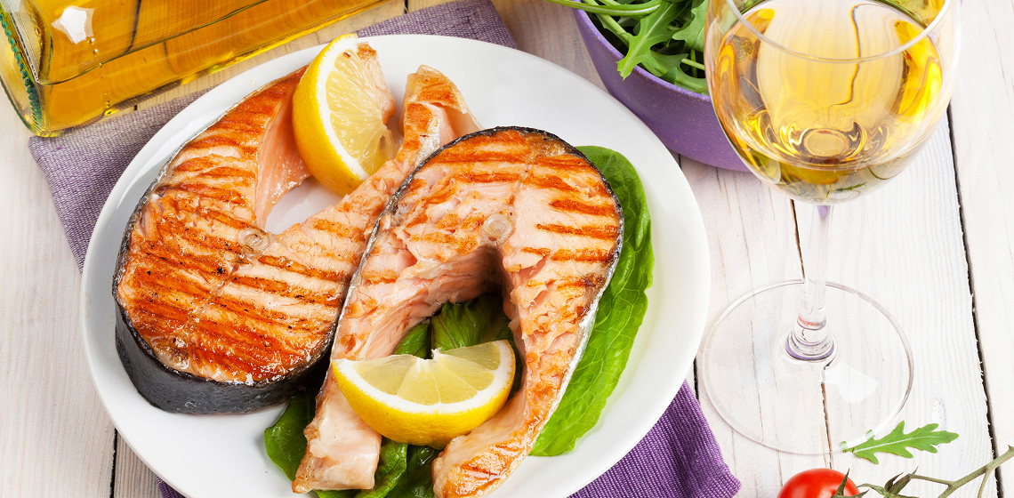 wines-go-well-with-sockeye-salmon Two sockeye salmon steaks on a plate with a glass of white wine